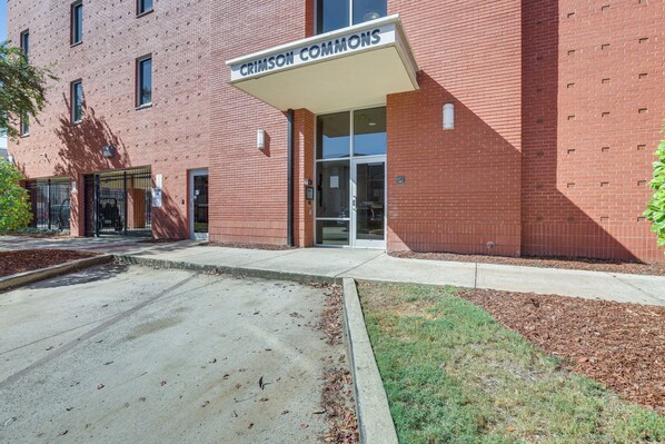 A brick building with a sign reading "CRIMSON COMMONS" at the entrance. - Walk to UA Campus: Apt w/ Secure Parking! (Tuscaloosa)