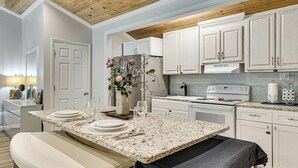 A modern kitchen with white cabinetry, a granite countertop, and a dining area with a bench. - 6 Mi to Clarks Hill Lake: Quiet Couple's Retreat (Appling)
