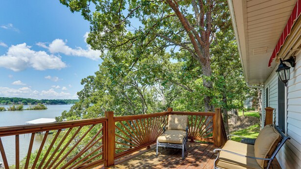 A wooden deck with a view of a lake, a chair, and a small table. - Ozarks Waterfront Home w/ Dock & Marina Access (Warsaw)