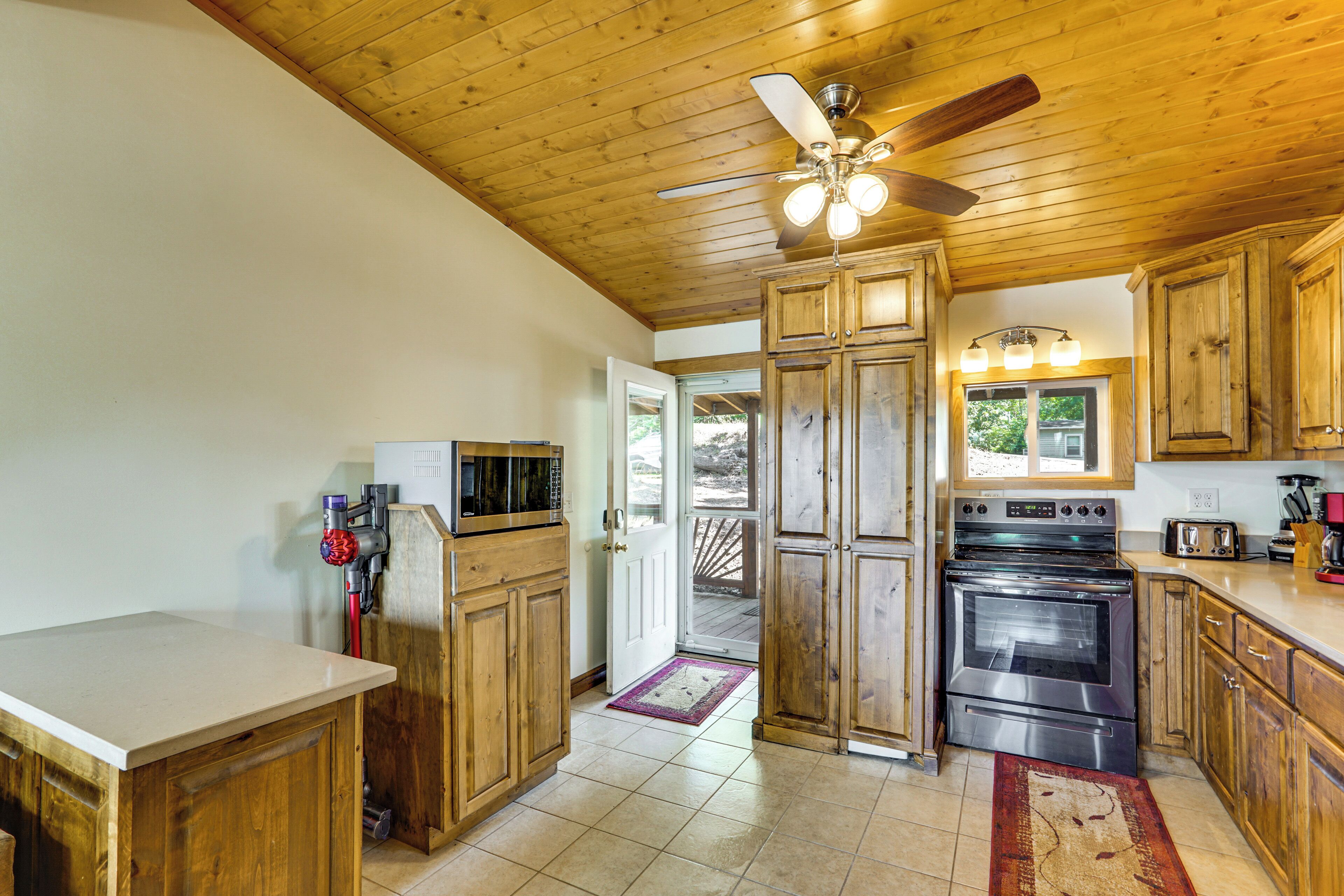 A kitchen with wooden cabinets, a stainless steel oven, a microwave, and a ceiling fan.