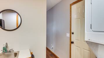 A bathroom with a sink, mirror, and a white door.