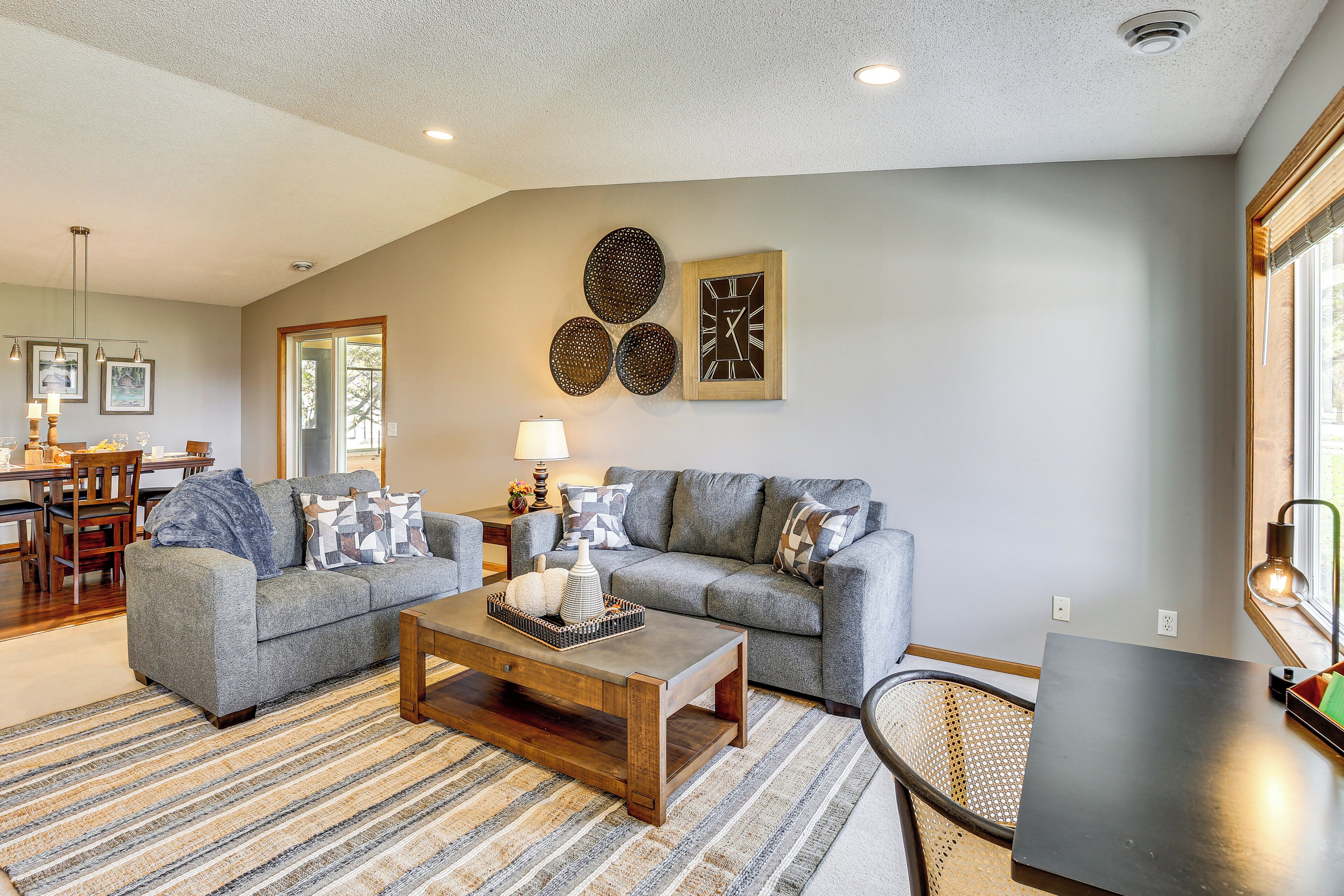 A living room with two grey sofas, a coffee table, a patterned rug, and wall art.