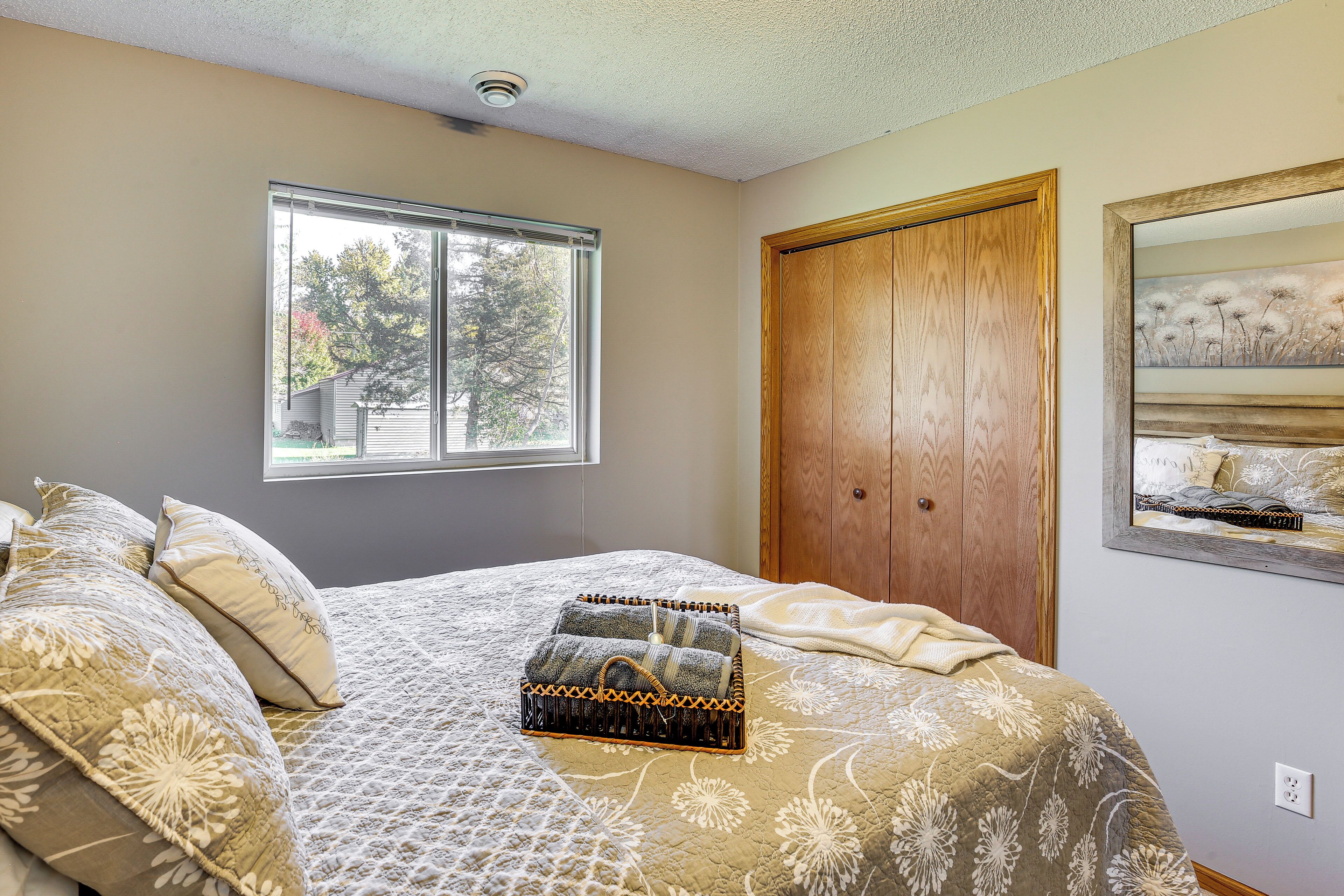 Une chambre à coucher avec un lit, une fenêtre, une porte en bois et un tableau accroché au mur.