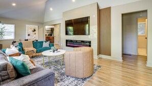 A modern living room with a large flat-screen TV, a fireplace, and a cozy seating area. - Close to Decatur Square: Family Home w/ Deck! (Decatur)