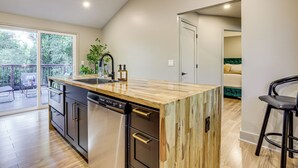 A modern kitchen with a wooden island, stainless steel appliances, and a sliding glass door leading to an outdoor patio. - Close to Decatur Square: Family Home w/ Deck! (Decatur)