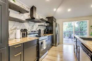 A modern kitchen with dark cabinetry, stainless steel appliances, and a marble backsplash. - Close to Decatur Square: Family Home w/ Deck! (Decatur)