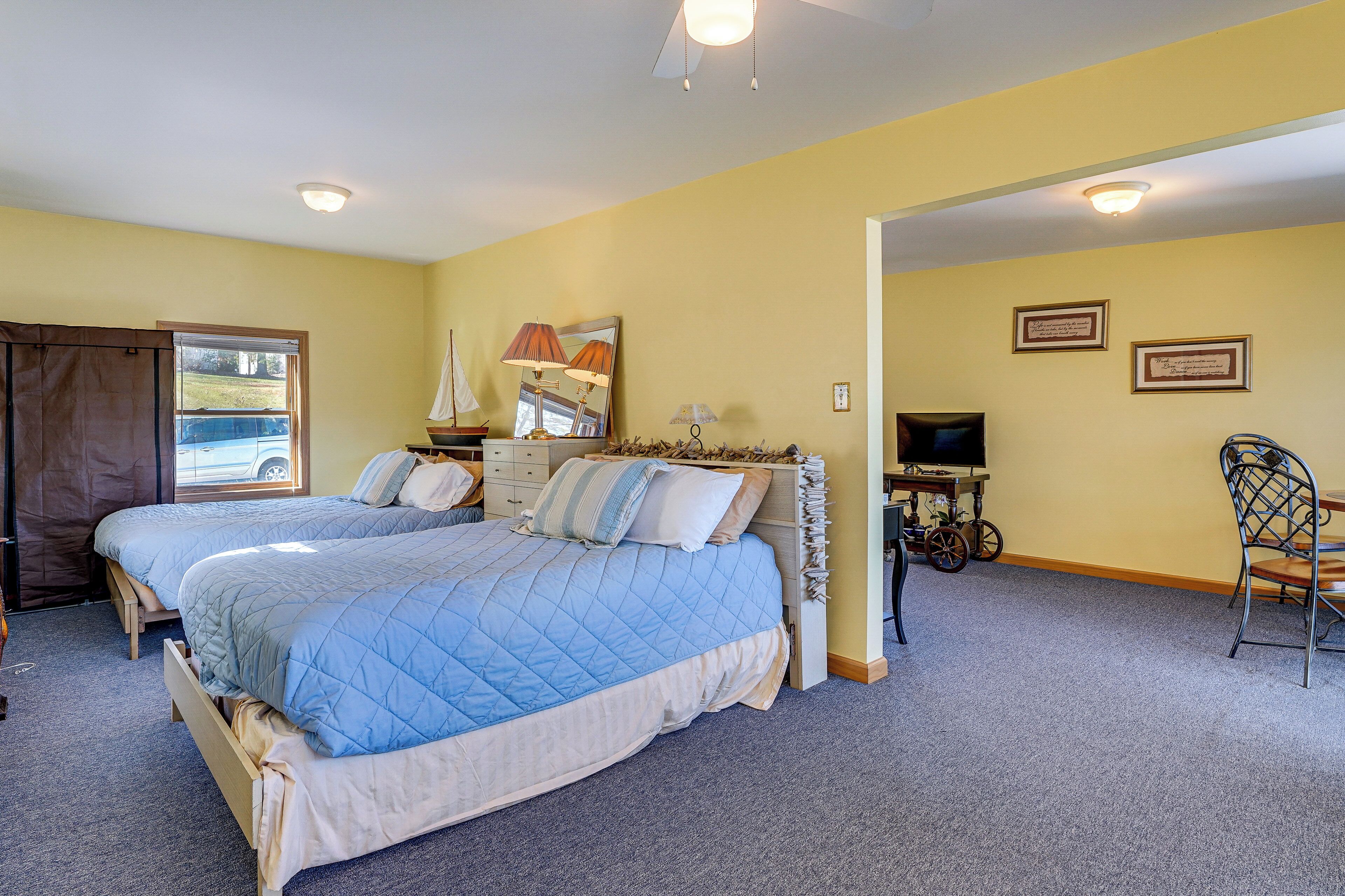 A bedroom with two beds, a desk, a chair, and a television.