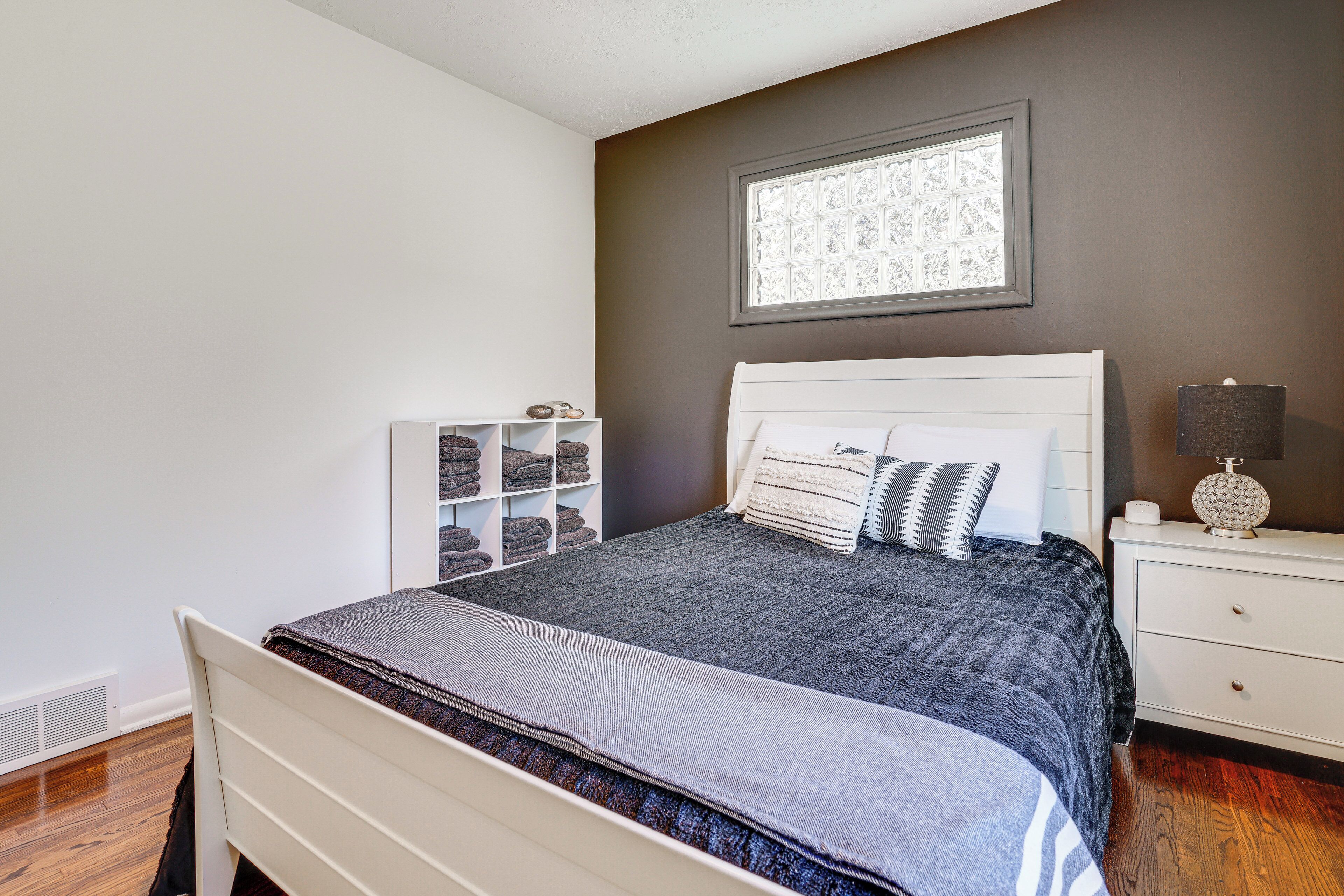 A neatly arranged bedroom with a bed, bedside table, and a built-in shelving unit.