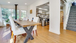 A modern kitchen with white brick walls, a wooden dining table, and a staircase. - Cabin w/ Halstead Bay Access: Hot Tub, Sauna, Dock (Mound)
