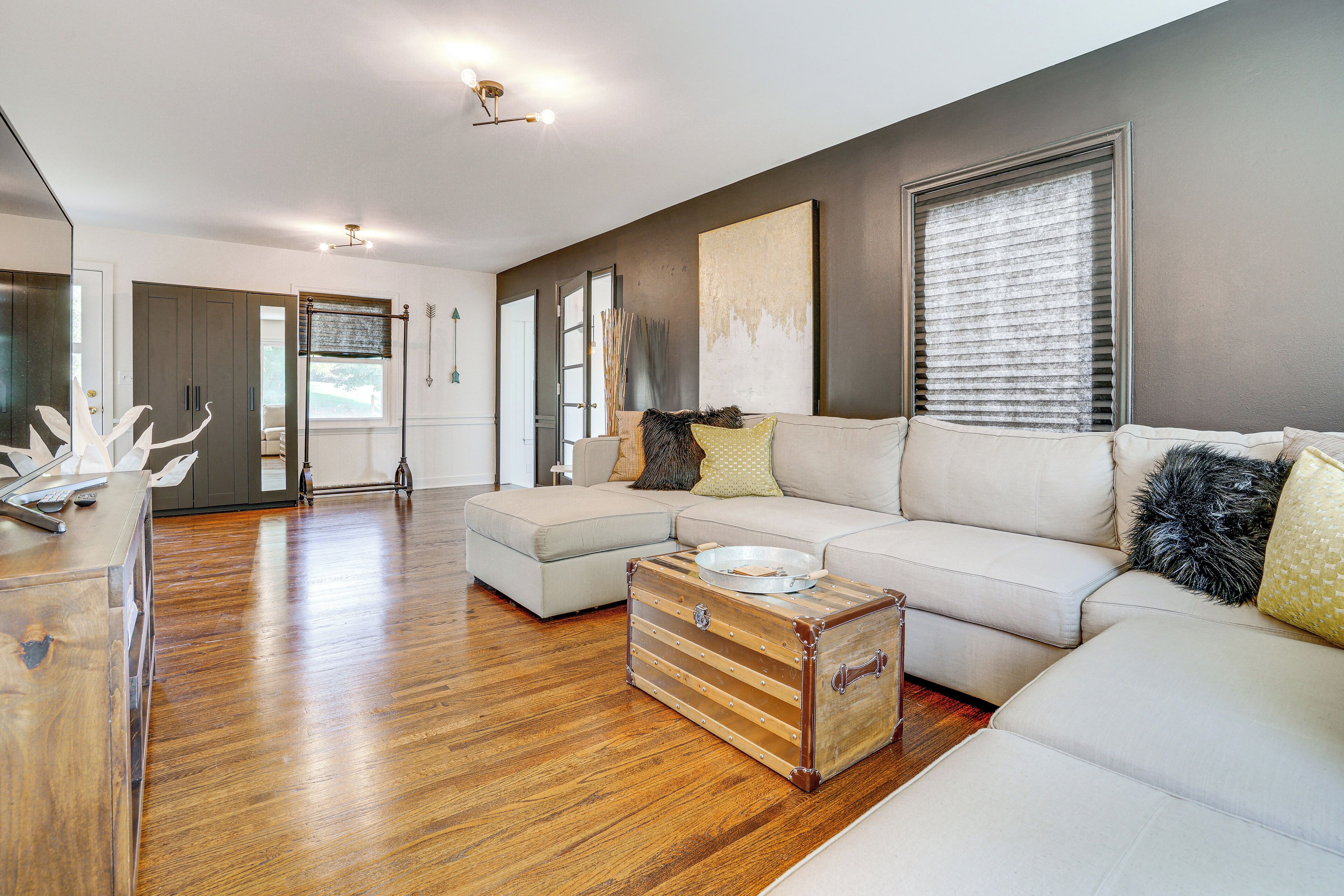 A spacious living room with a large sectional sofa, a wooden coffee table, and a vintage suitcase.
