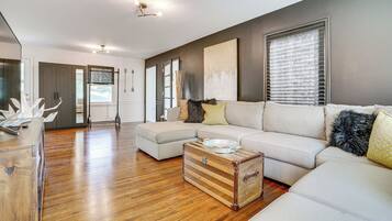 A spacious living room with a large sectional sofa, a wooden coffee table, and a vintage suitcase.