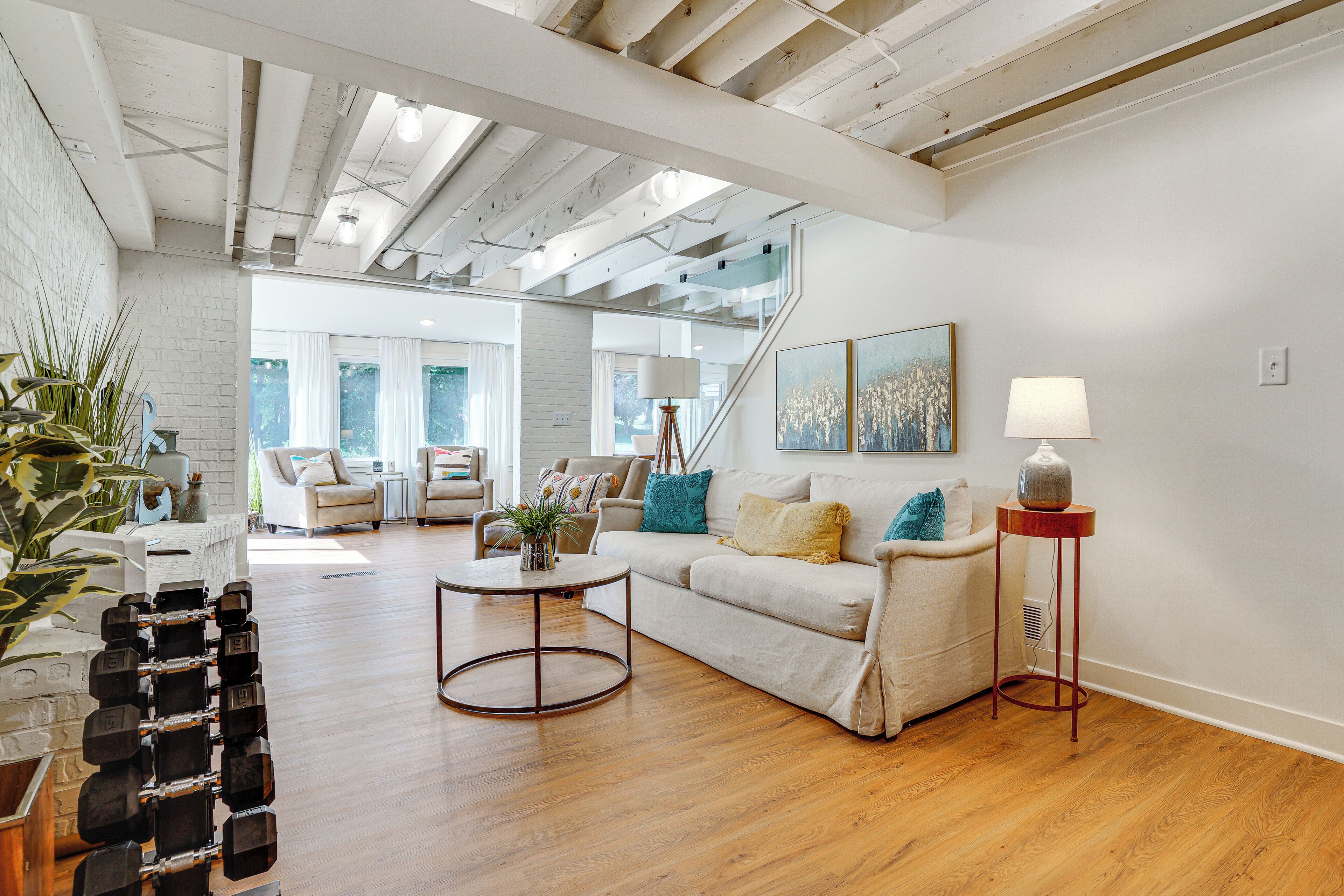 A spacious living room with a wooden floor, a sofa, a coffee table, and a staircase leading to another level.