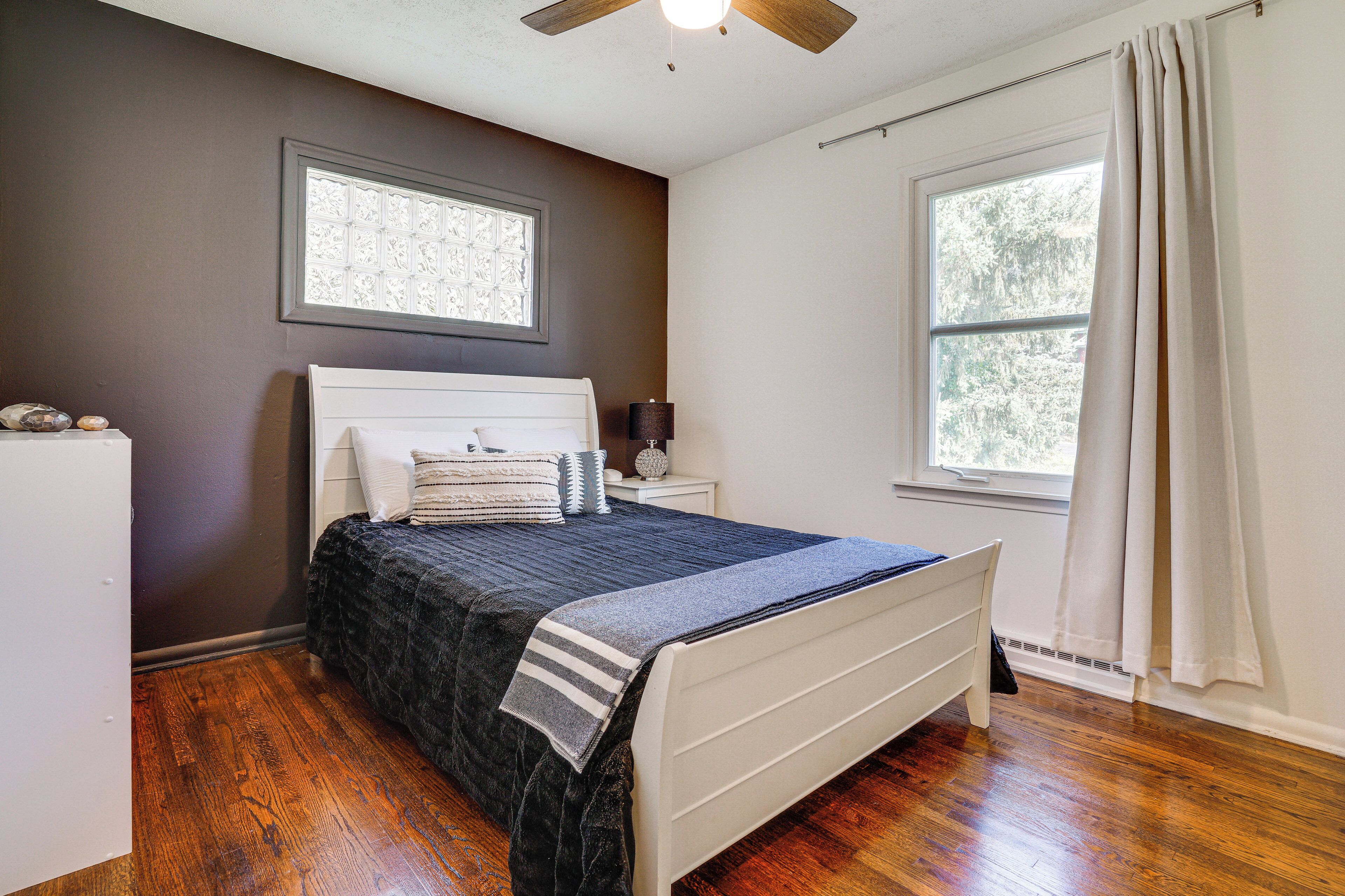 A bedroom with a bed, nightstand, and a window with curtains.