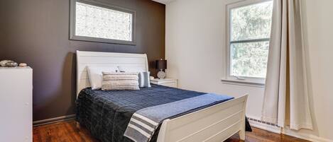 A bedroom with a bed, nightstand, and a window with curtains.