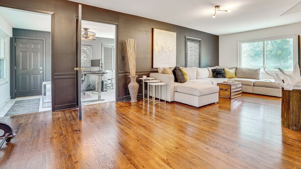 A spacious living room with hardwood flooring, a white sofa, a small coffee table, and a large window providing natural light. - Cabin w/ Halstead Bay Access: Hot Tub, Sauna, Dock (Mound)