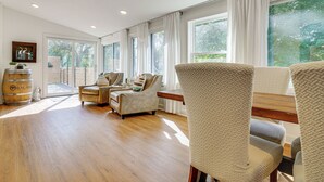 A spacious living room with a wooden floor, a sofa, a chair, and a dining table. - Cabin w/ Halstead Bay Access: Hot Tub, Sauna, Dock (Mound)