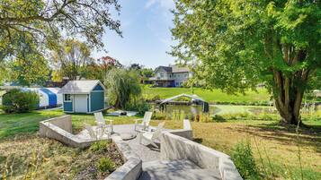 A residential area with a small house, a pond, and a deck with chairs.
