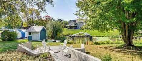 A residential area with a small house, a pond, and a deck with chairs.
