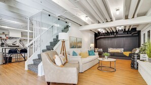 A spacious living area with a staircase, a sofa set, a coffee table, and a kitchen in the background. - Cabin w/ Halstead Bay Access: Hot Tub, Sauna, Dock (Mound)