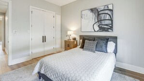 A bedroom with a large bed, a nightstand with a lamp, a wardrobe, and a wall-mounted abstract painting. - Walk to Shops & Winery! Stylish Dtwn Ovilla Home (Red Oak)