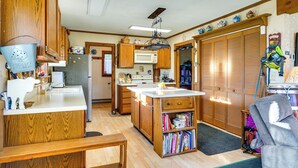 A compact kitchen with wooden cabinets, a central island, and a dining area with a bench. - Relaxation Meets Upstate Adventure at Salem Home! (Salem)