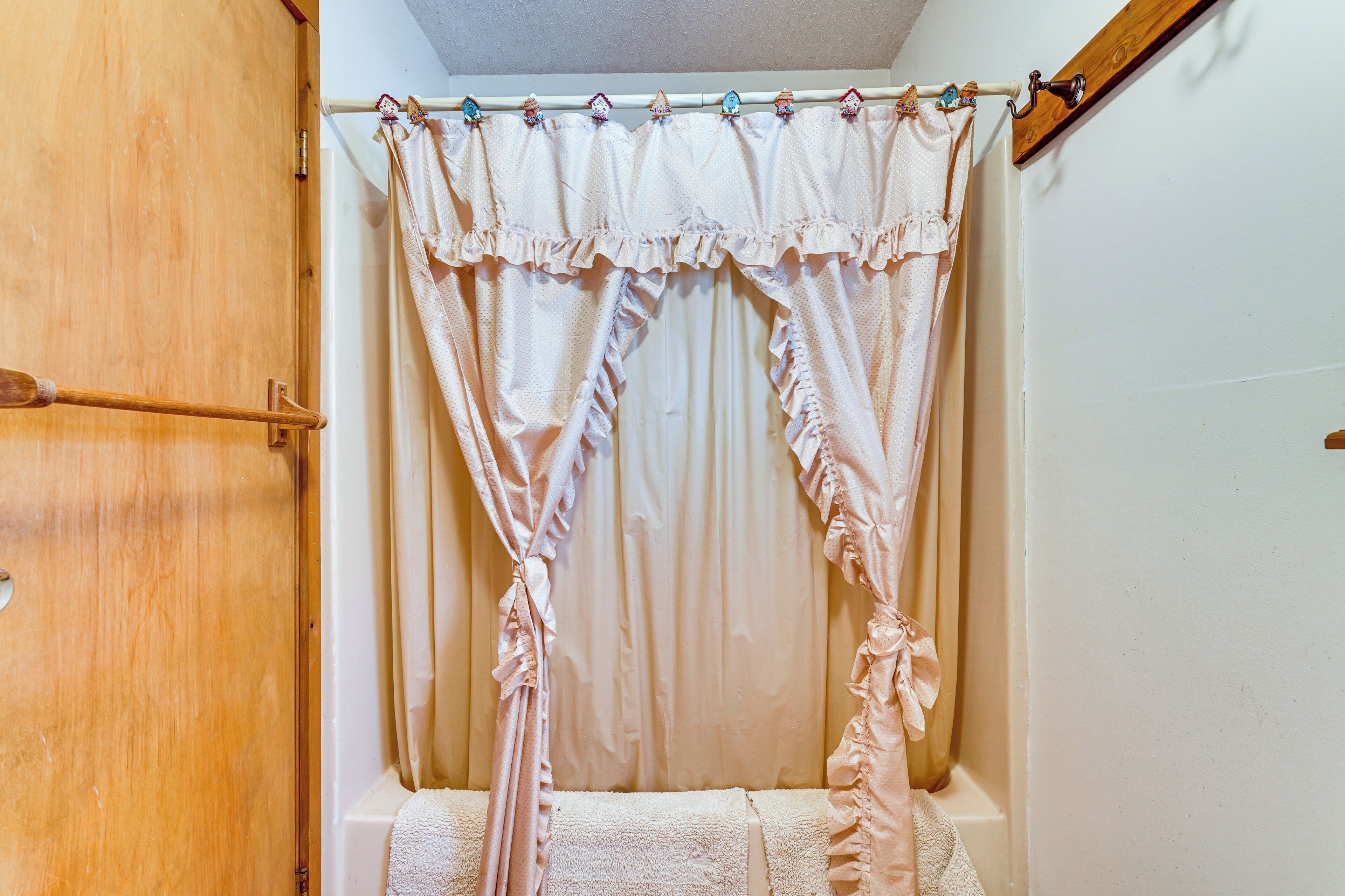 Une salle de bain avec une porte en bois, un rideau de douche et un porte-serviettes.