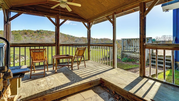 A covered outdoor deck with wooden chairs and a table, overlooking a grassy area and hills. - Relaxation Meets Upstate Adventure at Salem Home! (Salem)