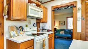 A compact kitchen with wooden cabinets, a white stove, and a microwave. - Relaxation Meets Upstate Adventure at Salem Home! (Salem)