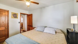 A bedroom with a bed, a nightstand, a lamp, a ceiling fan, and a door. - Walk to Restaurant & Bar: Home w/ Deck in Gary (Gary)