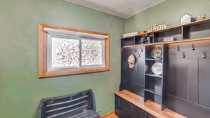 A room with a window, a black chair, a wooden bench, and a black cabinet with shelves. - Walk to Restaurant & Bar: Home w/ Deck in Gary (Gary)