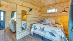 A cozy wooden cabin room with a bed, a chair, a mirror, and a window. - Pond & Grazing Cattle! Rural Getaway Near Van (Van)