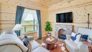 A cozy cabin interior with a fireplace, a television mounted on the wall, and a comfortable seating area with a sofa and armchairs. - Pond & Grazing Cattle! Rural Getaway Near Van (Van)