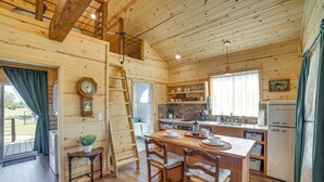 A wooden cabin interior with a kitchen, dining area, and a staircase leading to a loft. - Pond & Grazing Cattle! Rural Getaway Near Van (Van)