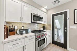 A modern kitchen with white cabinets, a Bosch microwave, a toaster, and a stove.