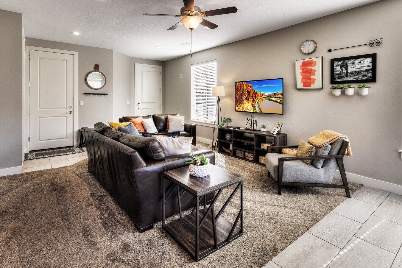 A living room with a sofa, coffee table, armchair, TV, and a ceiling fan.