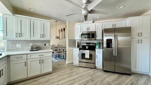 Una cucina moderna con pensili bianchi, elettrodomestici in acciaio inossidabile e una ventola a soffitto.