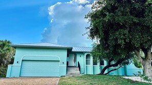 A single-story house with a light blue exterior, a garage door, and a staircase leading to the front door.