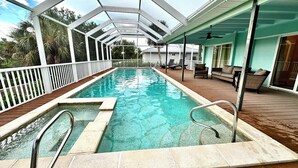 Una piscina con un pontile in legno e una zona coperta con posti a sedere.