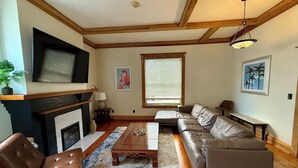 A living room with a fireplace, a sofa, a coffee table, and a television mounted on the wall.