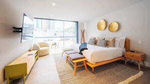 A modern bedroom with a large bed, a seating area, and a view of the city. - DUM Residences (Mexico City)