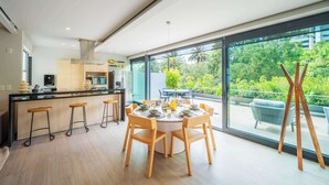 A modern kitchen with a central island, bar stools, and a dining area with a round table and chairs. - DUM Residences (Mexico City)