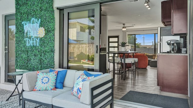 Un espace de vie moderne comprenant un canapé, une porte vitrée donnant sur un balcon et une cuisine visible à travers la vitre.