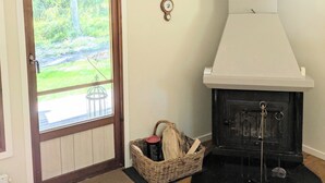 Una habitación con puerta de madera, chimenea y una cesta de mimbre con objetos.
