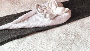 A neatly made bed with a patterned bedspread, two pillows with circular and leaf designs, and a folded towel on the bed. - Enchanting 2-bedroom apartment in Nelspruit (Nelspruit)