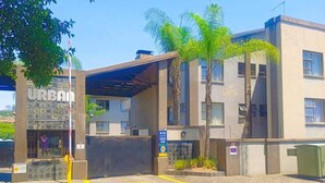 A building labeled "URBAN" with a covered entrance, palm trees, and a paved area with yellow lines. - Enchanting 2-bedroom apartment in Nelspruit (Nelspruit)