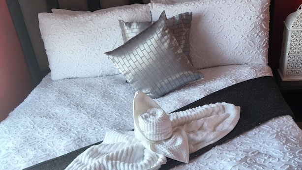 A neatly made bed with a patterned bedspread, pillows, and a folded towel. - Enchanting 2-bedroom apartment in Nelspruit (Nelspruit)