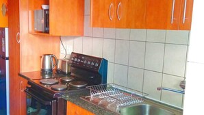 A kitchen with wooden cabinets, a stove, a sink, and a dish rack. - Enchanting 2-bedroom apartment in Nelspruit (Nelspruit)