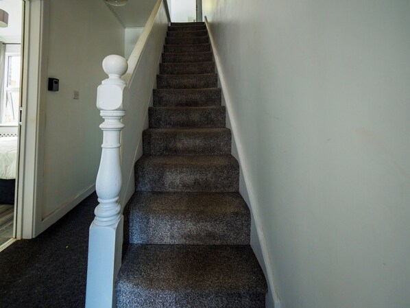 A staircase with dark carpeted steps and a white balustrade. - Ensuite4 Woodhouse private bath 2kitchen (Stoke-on-Trent)