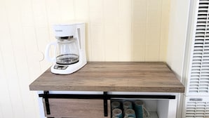 En køkkenbordplade med kaffemaskine, et fastgjort termostat og en hylde med krus.