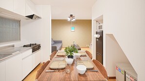 A modern kitchen with white cabinets, a wooden dining table set with plates, glasses, and a potted plant. - Experience life in a private old private house in the heart of Tokyo｜3 bedrooms, 5 beds｜Excellent access to Akasaka, Roppongi, Ginza, Aoyama, Harajuku, Imperial Palace｜with private workspace (港区)